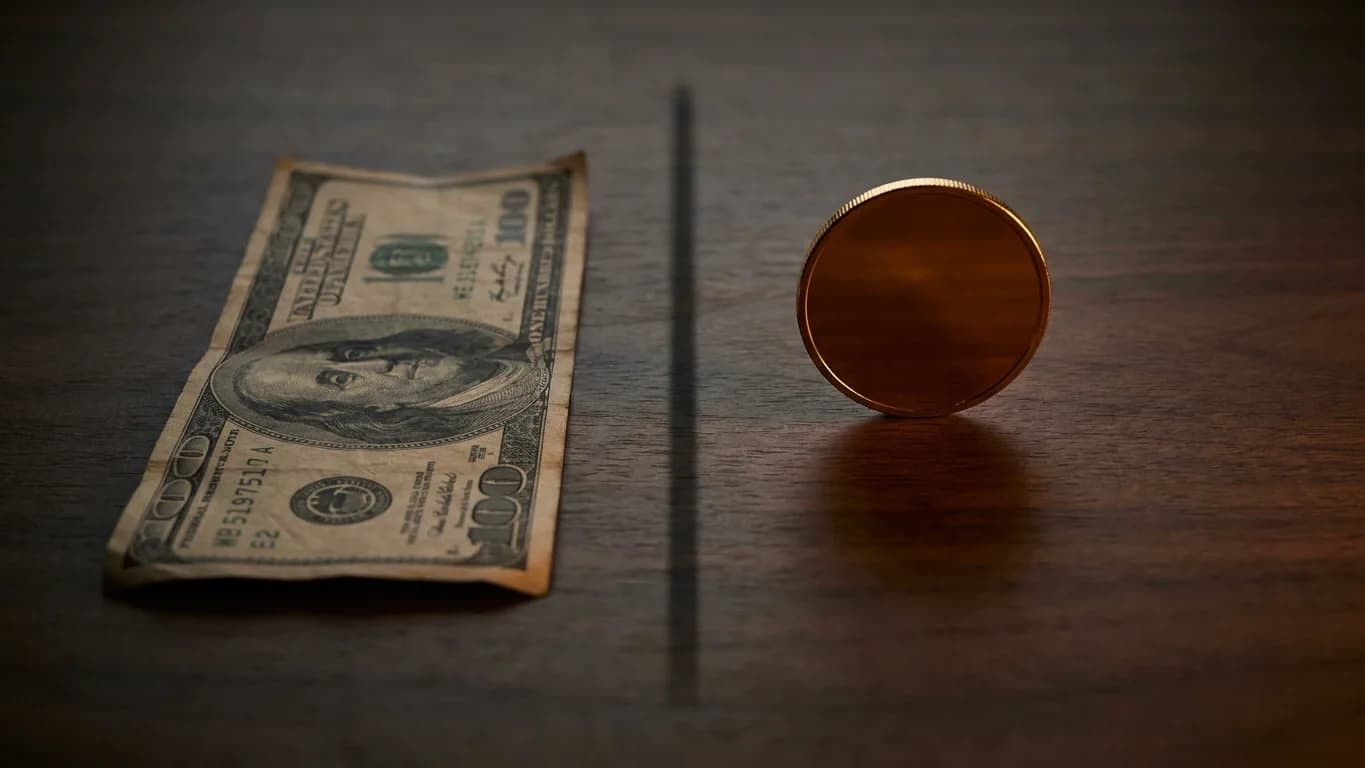 A worn paper banknote on one side, a single gold coin on the other — currency and money laid side by side