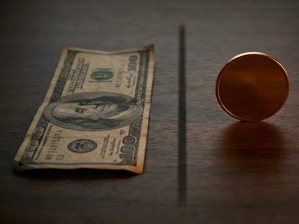 A worn paper banknote on one side, a single gold coin on the other — currency and money laid side by side